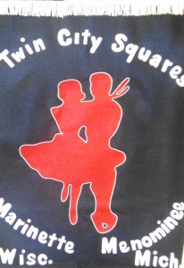 Dark banner with image of square dancing couple in red, and white lettering